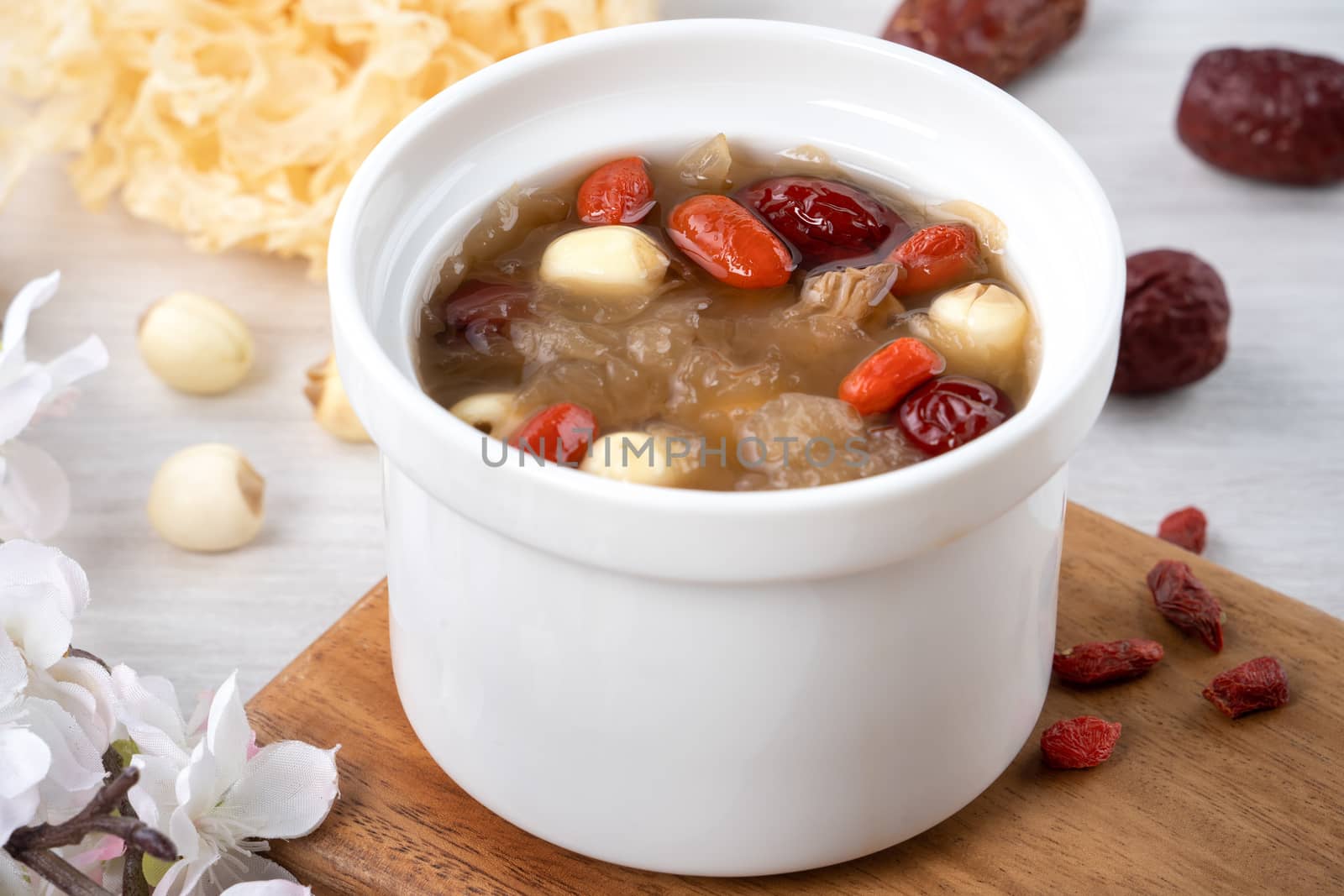 Close up of traditional Chinese sweet snow white fungus soup with lotus seed, red dates (jujube) and wolfberry (goji, gojiberry) on white background.