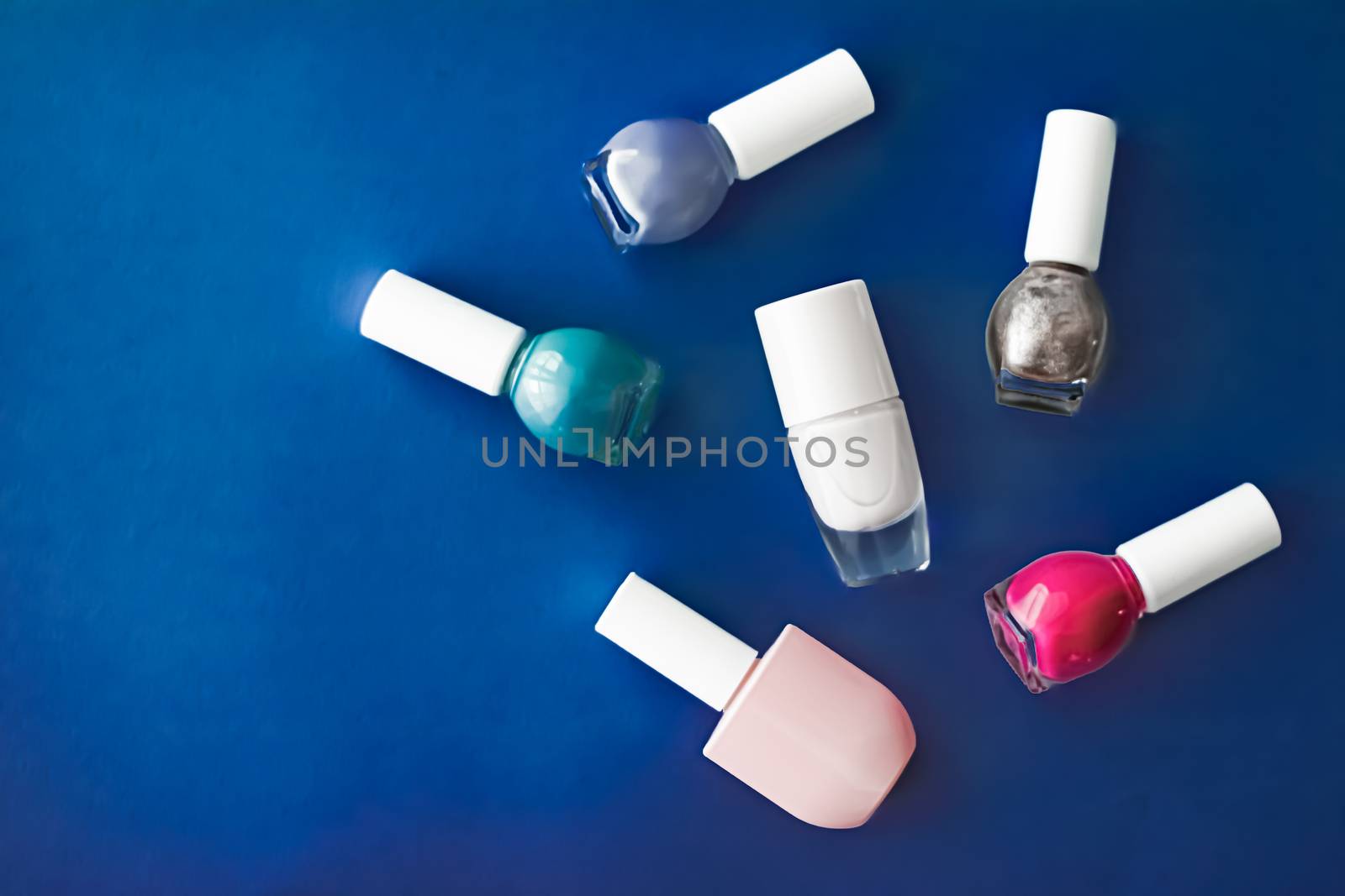 Nail polish bottles on dark blue background, beauty brand by Anneleven