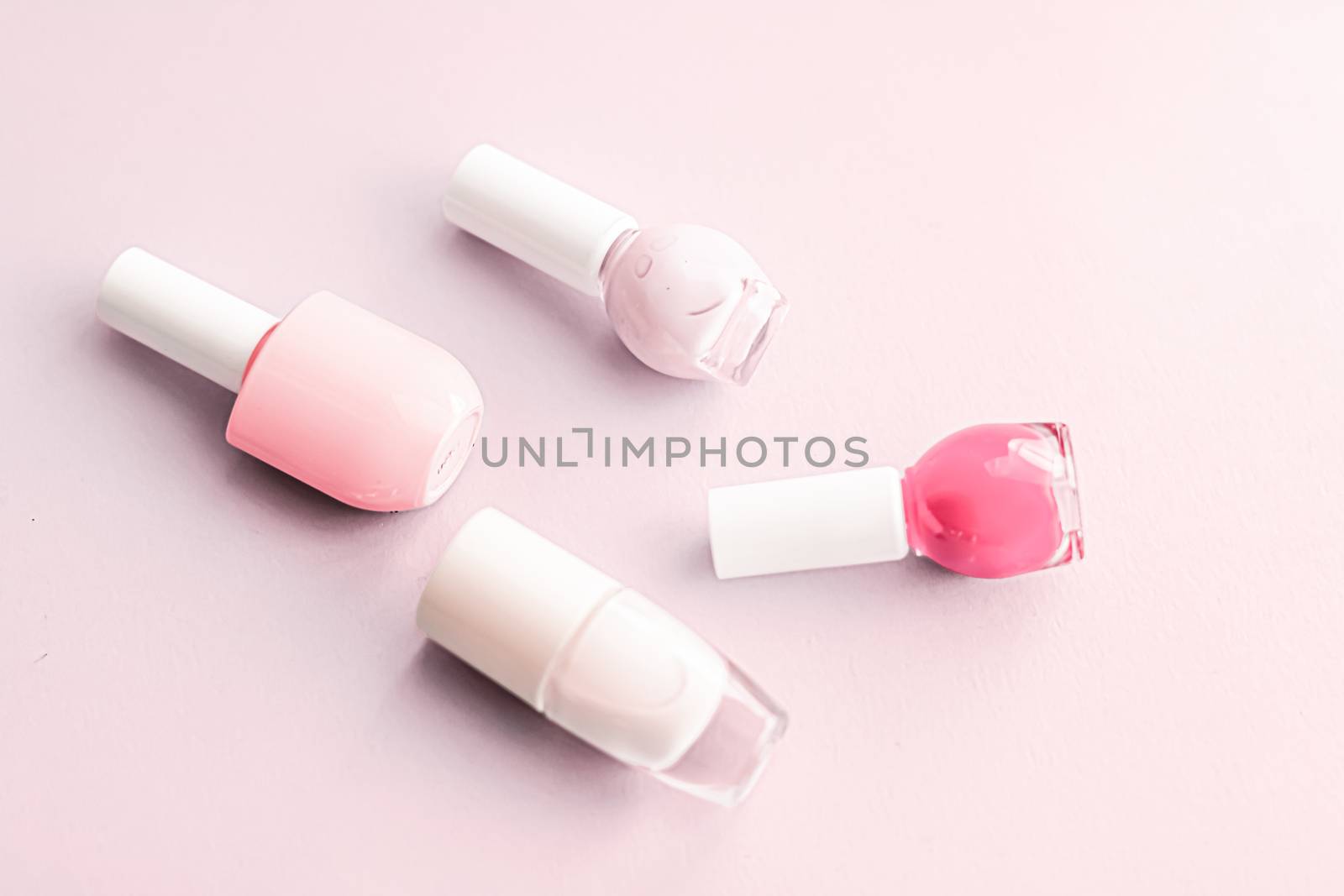 Nail polish bottles on blush pink background, beauty brand by Anneleven