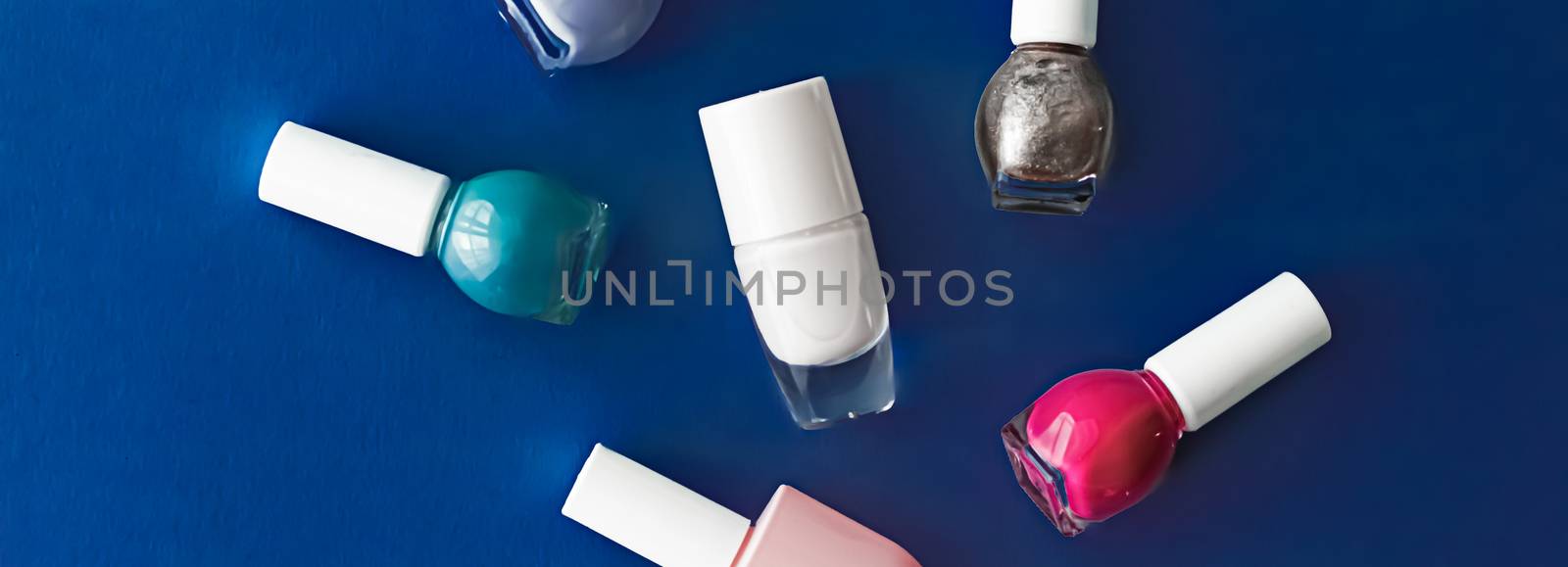 Nail polish bottles on dark blue background, beauty branding