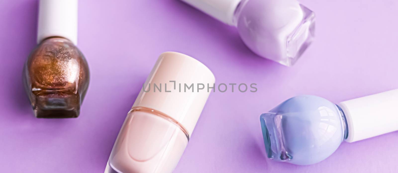 Nail polish bottles on purple background, beauty branding