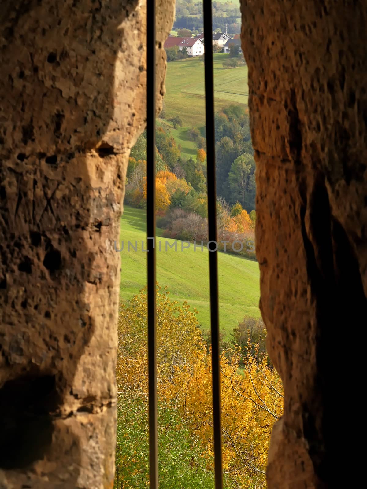 view through a castle loopholes to autumnal colored Germany