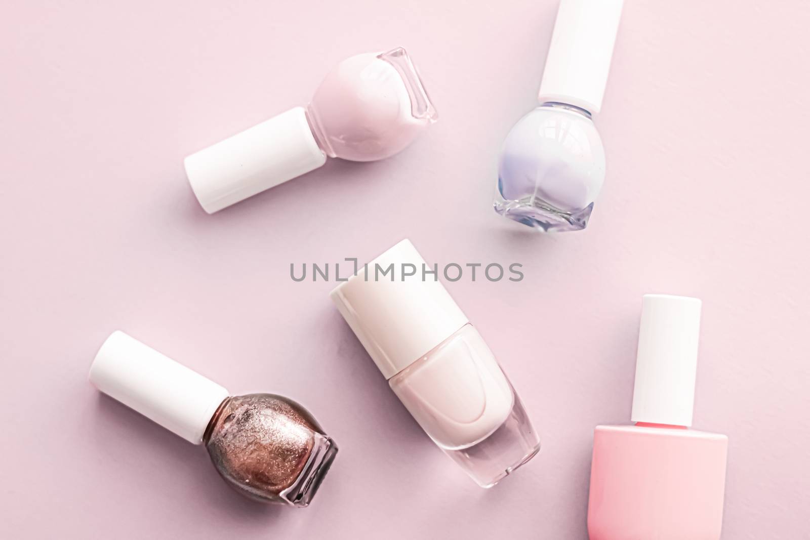 Nail polish bottles on blush pink background, beauty branding