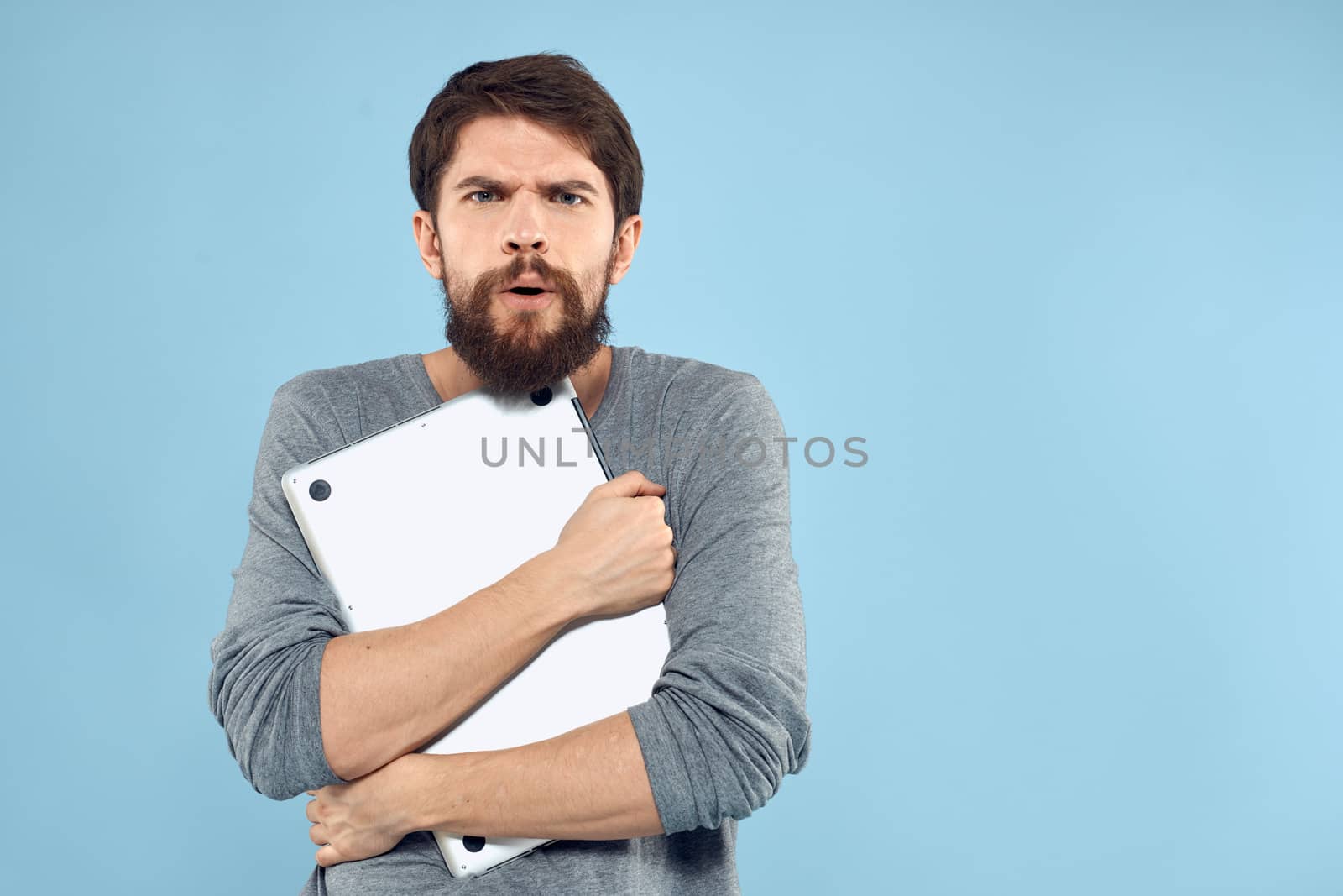 Bearded man laptop in hand internet wireless technology emotions blue background. High quality photo