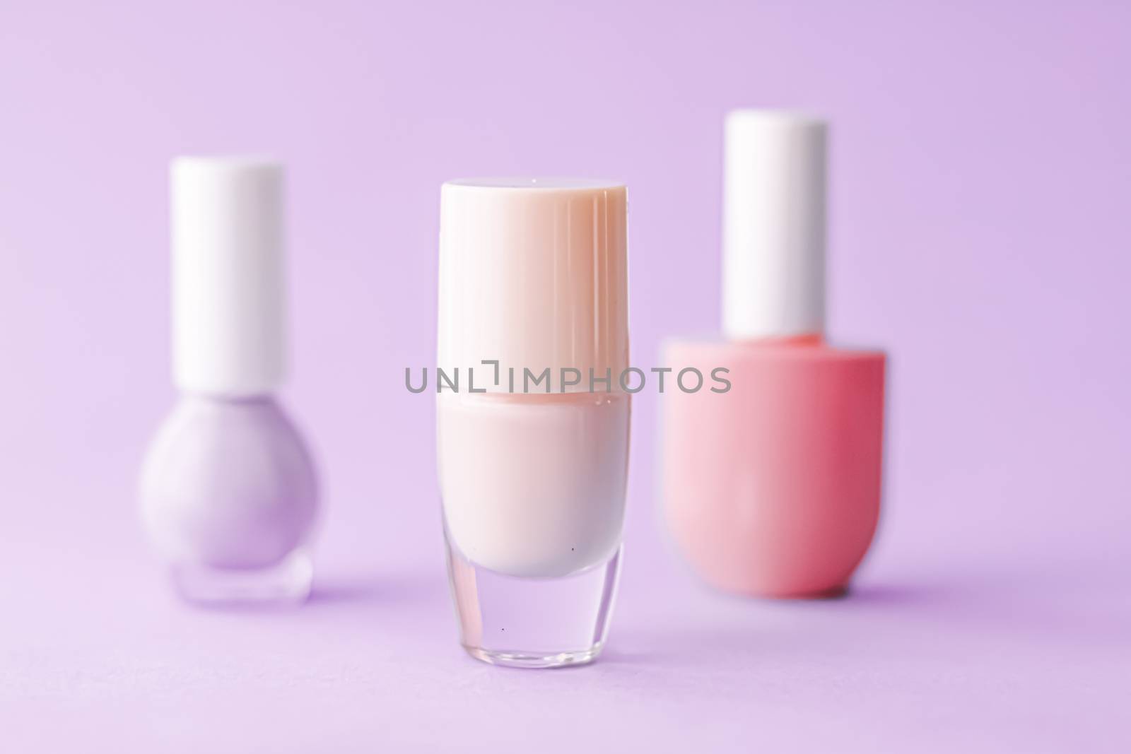 Nail polish bottles on purple background, beauty brand by Anneleven