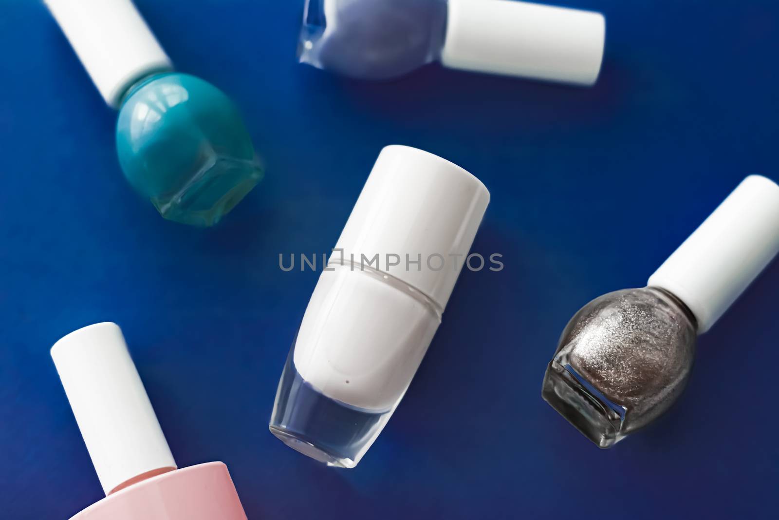 Nail polish bottles on dark blue background, beauty branding