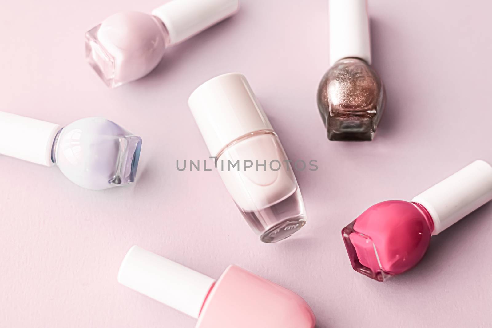 Nail polish bottles on blush pink background, beauty brand by Anneleven