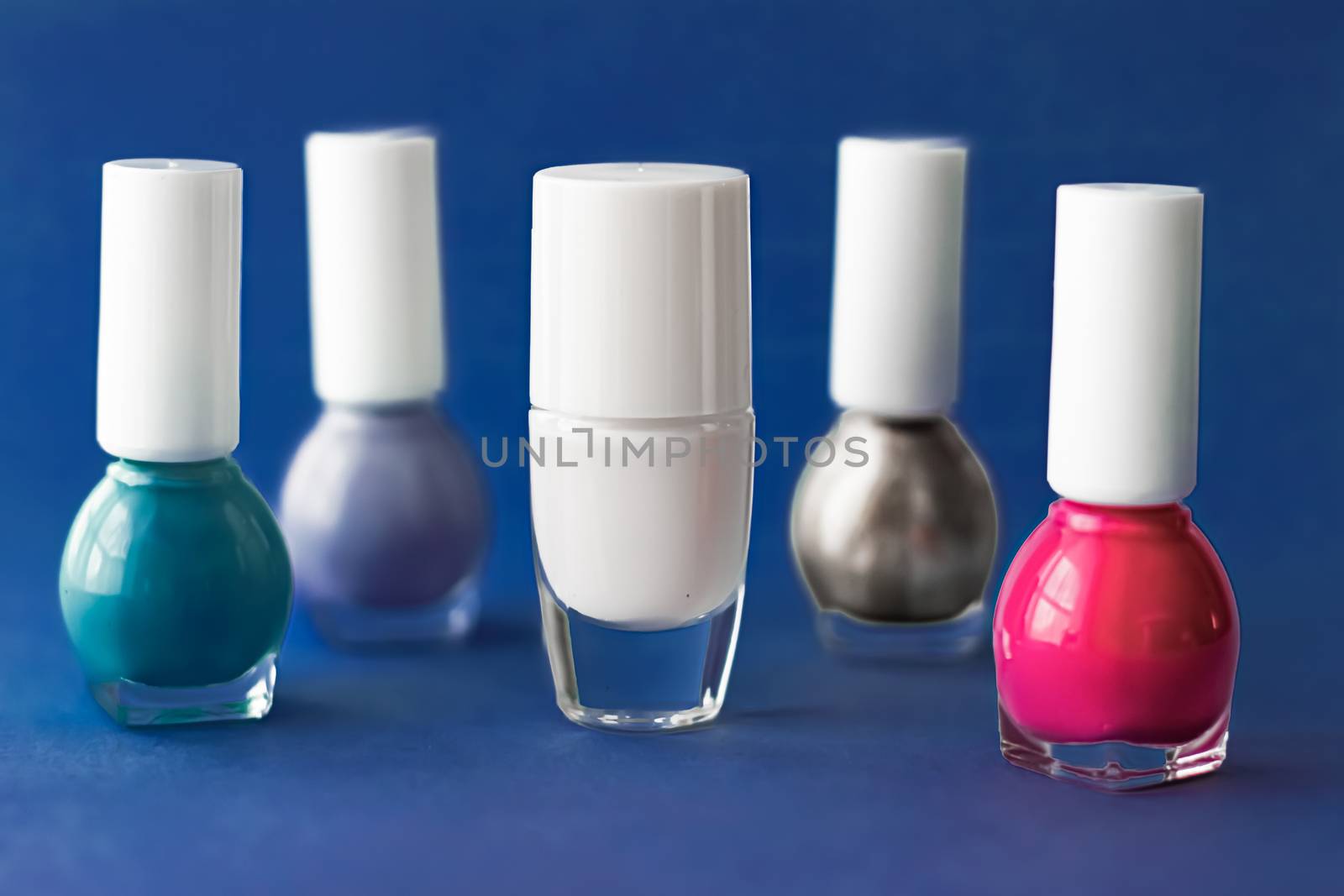 Nail polish bottles on dark blue background, beauty branding