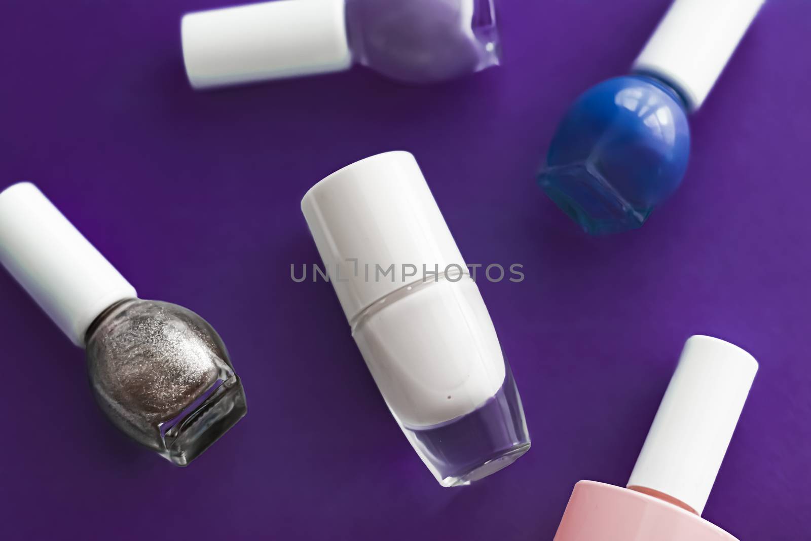 Nail polish bottles on dark purple background, beauty branding