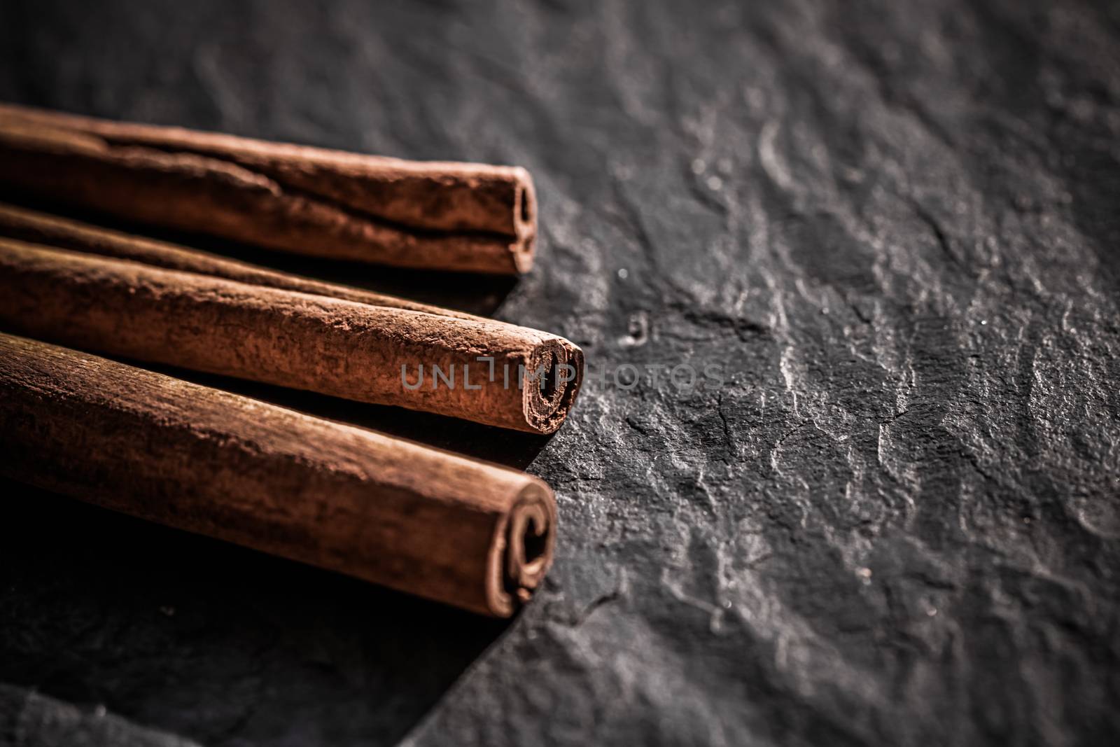 Cinnamon sticks on black stone background, food recipe by Anneleven