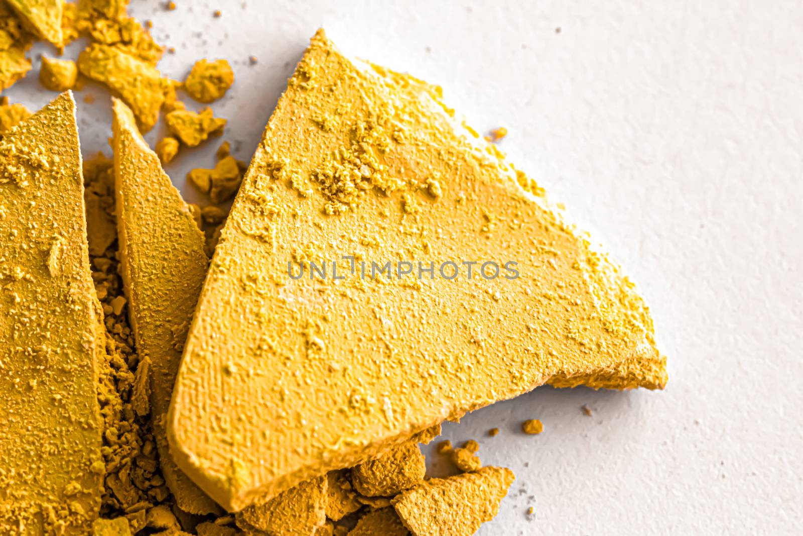 Yellow eye shadow powder as makeup palette closeup isolated on white background, crushed cosmetics and beauty textures