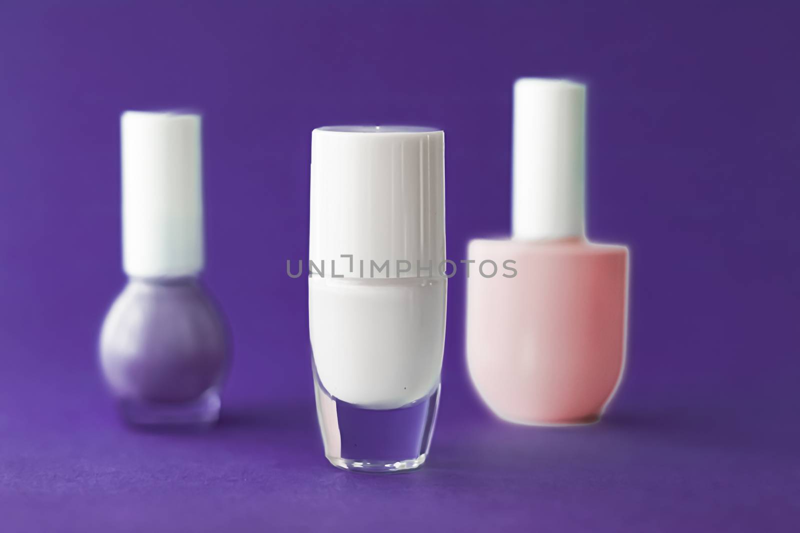 Nail polish bottles on dark purple background, beauty branding