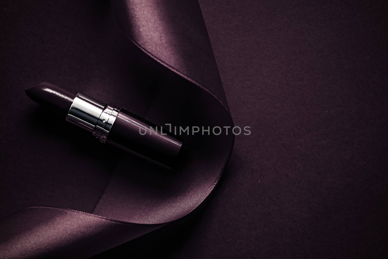 Luxury lipstick and silk ribbon on dark purple holiday backgroun by Anneleven