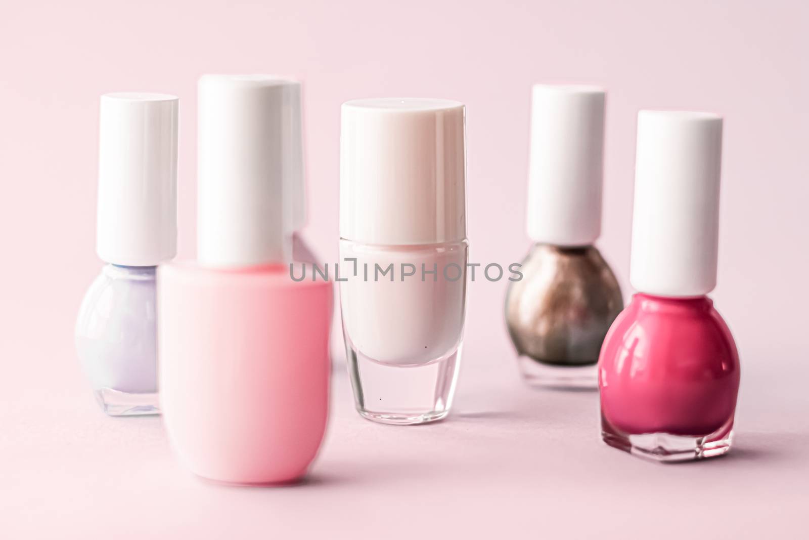 Nail polish bottles on blush pink background, beauty branding