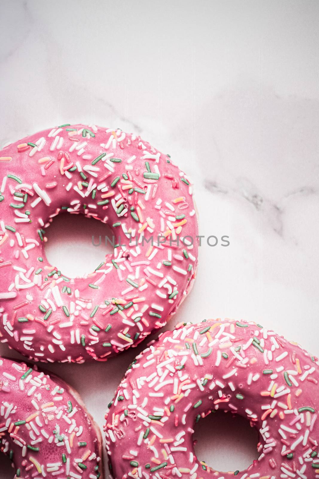 Frosted sprinkled donuts, sweet pastry dessert on marble table b by Anneleven