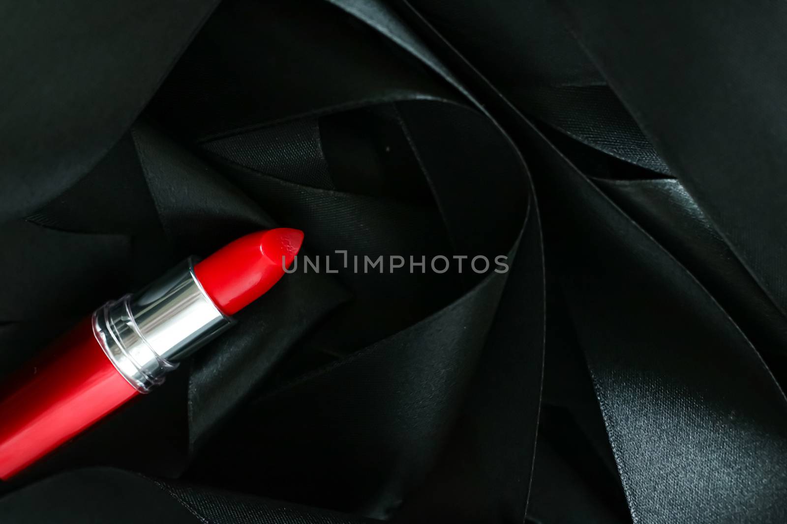 Red lipstick on black silk background, luxury make-up and beauty by Anneleven