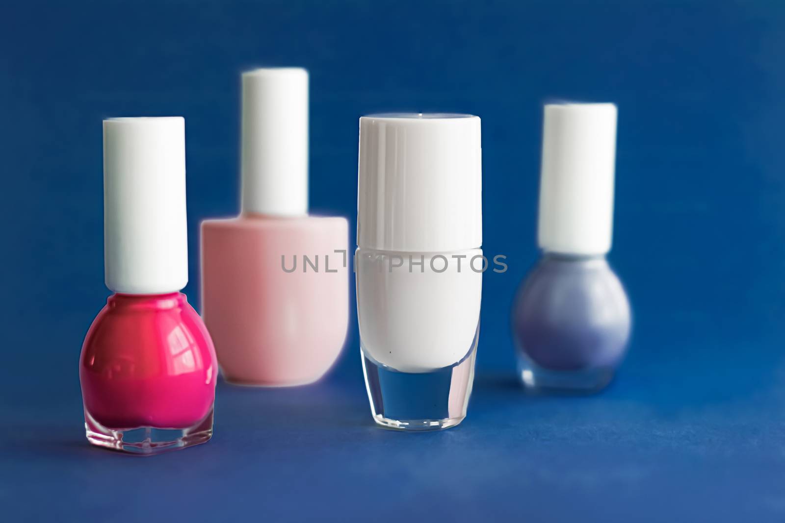 Nail polish bottles on dark blue background, beauty branding