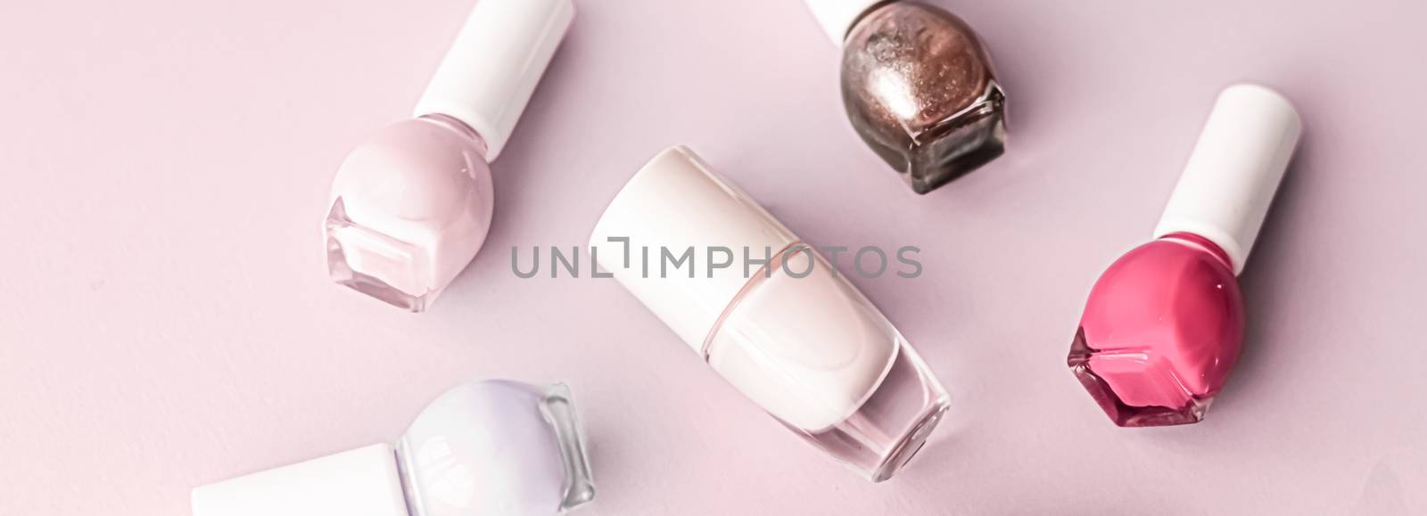 Nail polish bottles on blush pink background, beauty branding