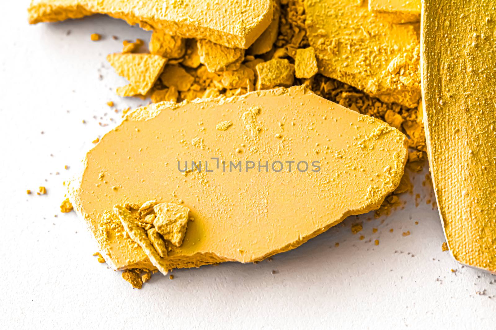 Yellow eye shadow powder as makeup palette closeup isolated on white background, crushed cosmetics and beauty textures