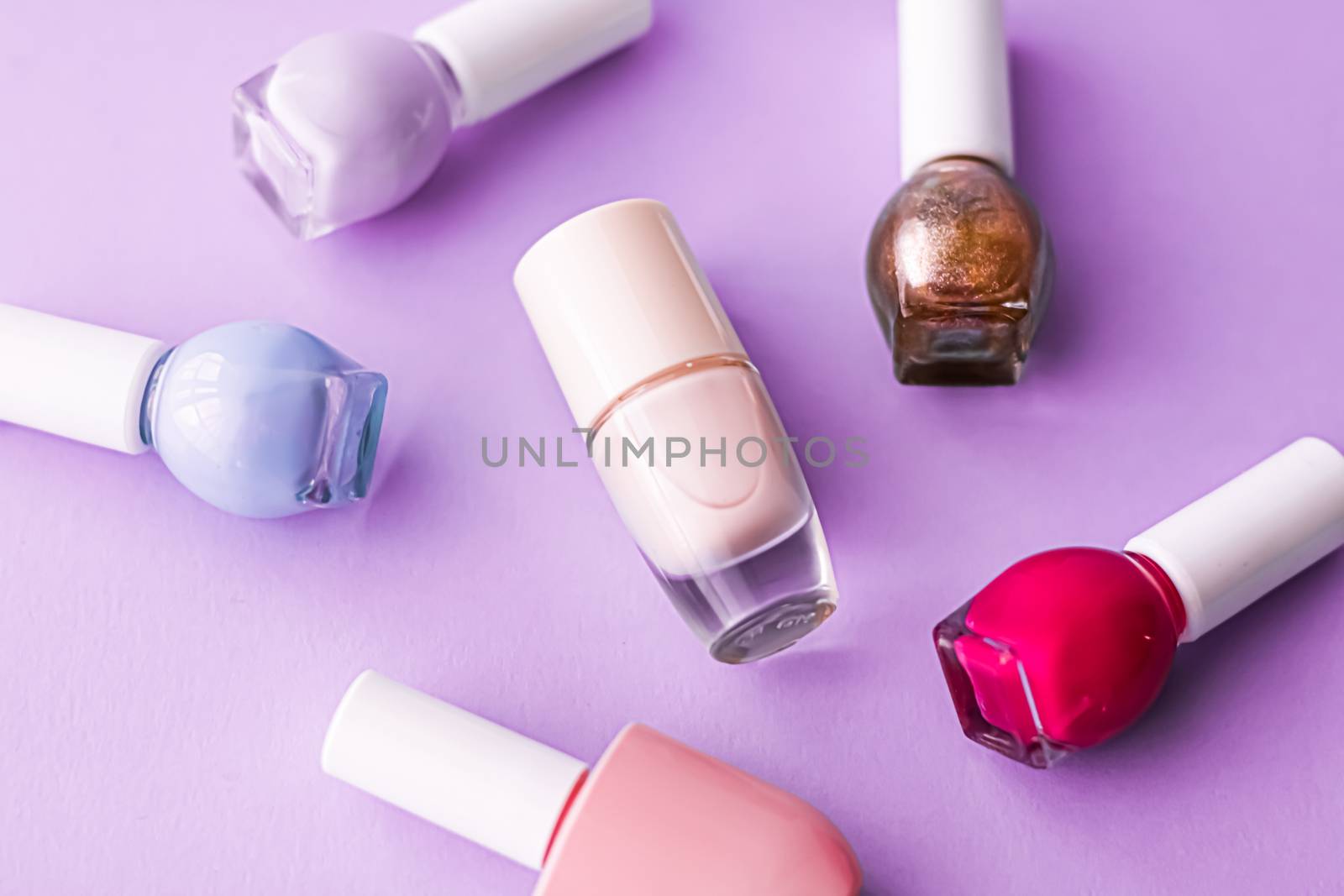 Nail polish bottles on purple background, beauty branding