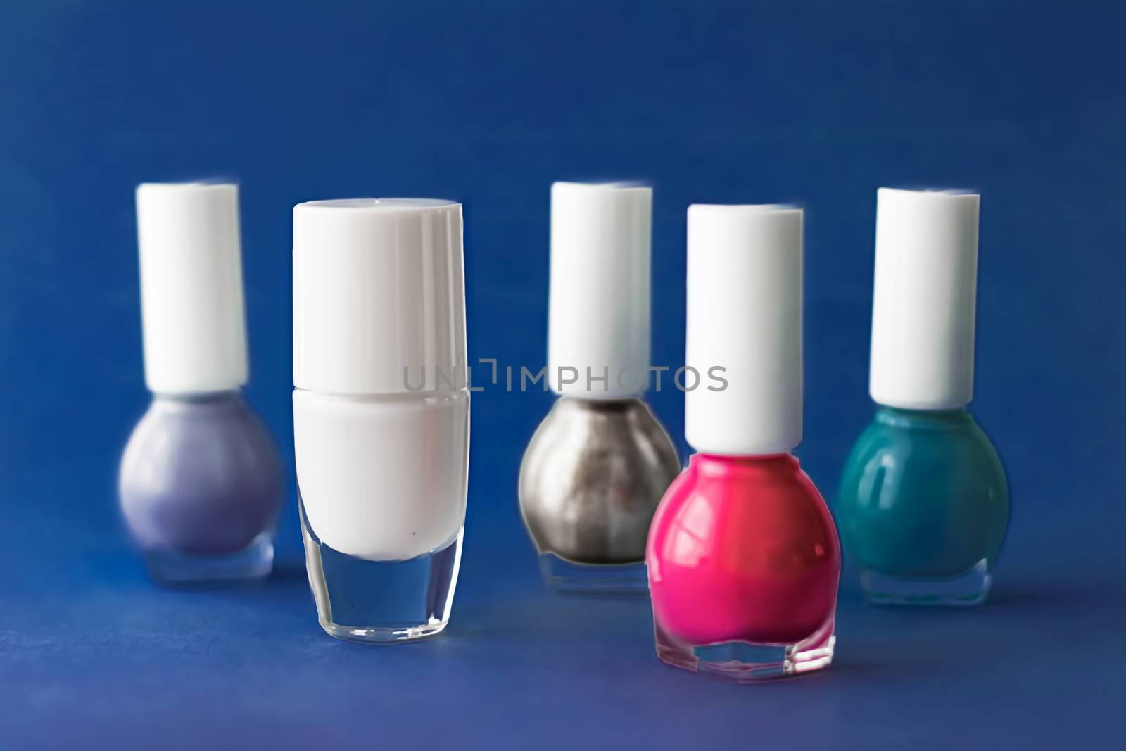 Nail polish bottles on dark blue background, beauty branding