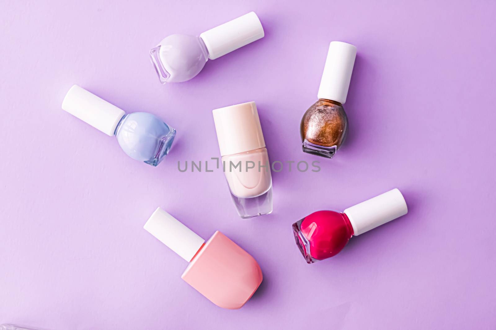 Nail polish bottles on purple background, beauty branding