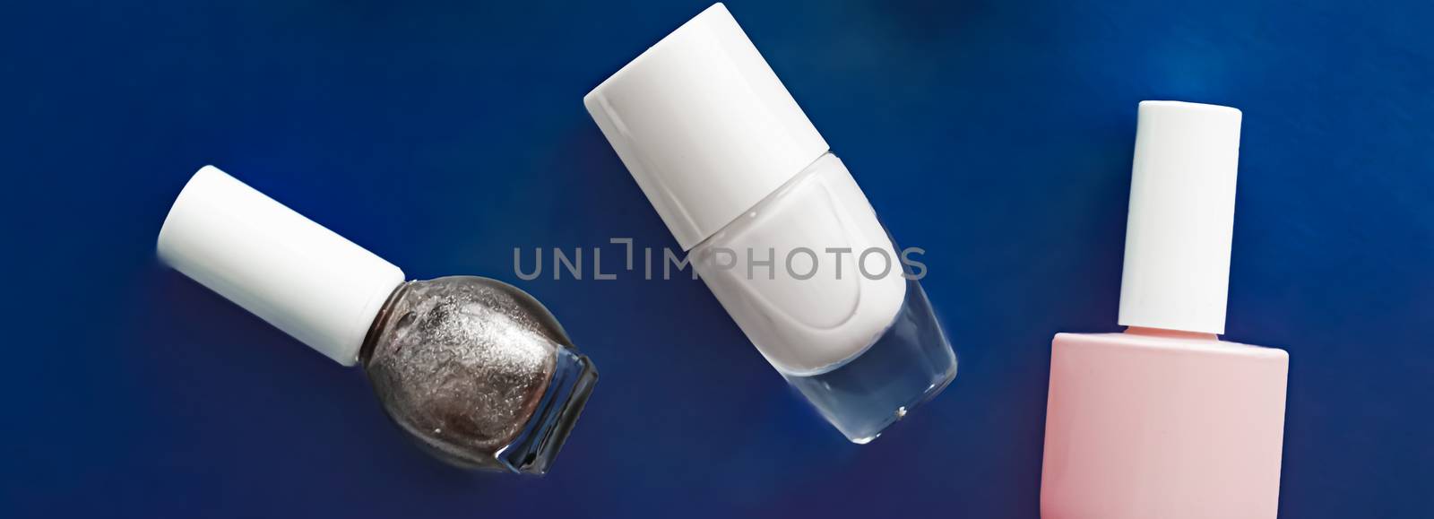 Nail polish bottles on dark blue background, beauty brand by Anneleven