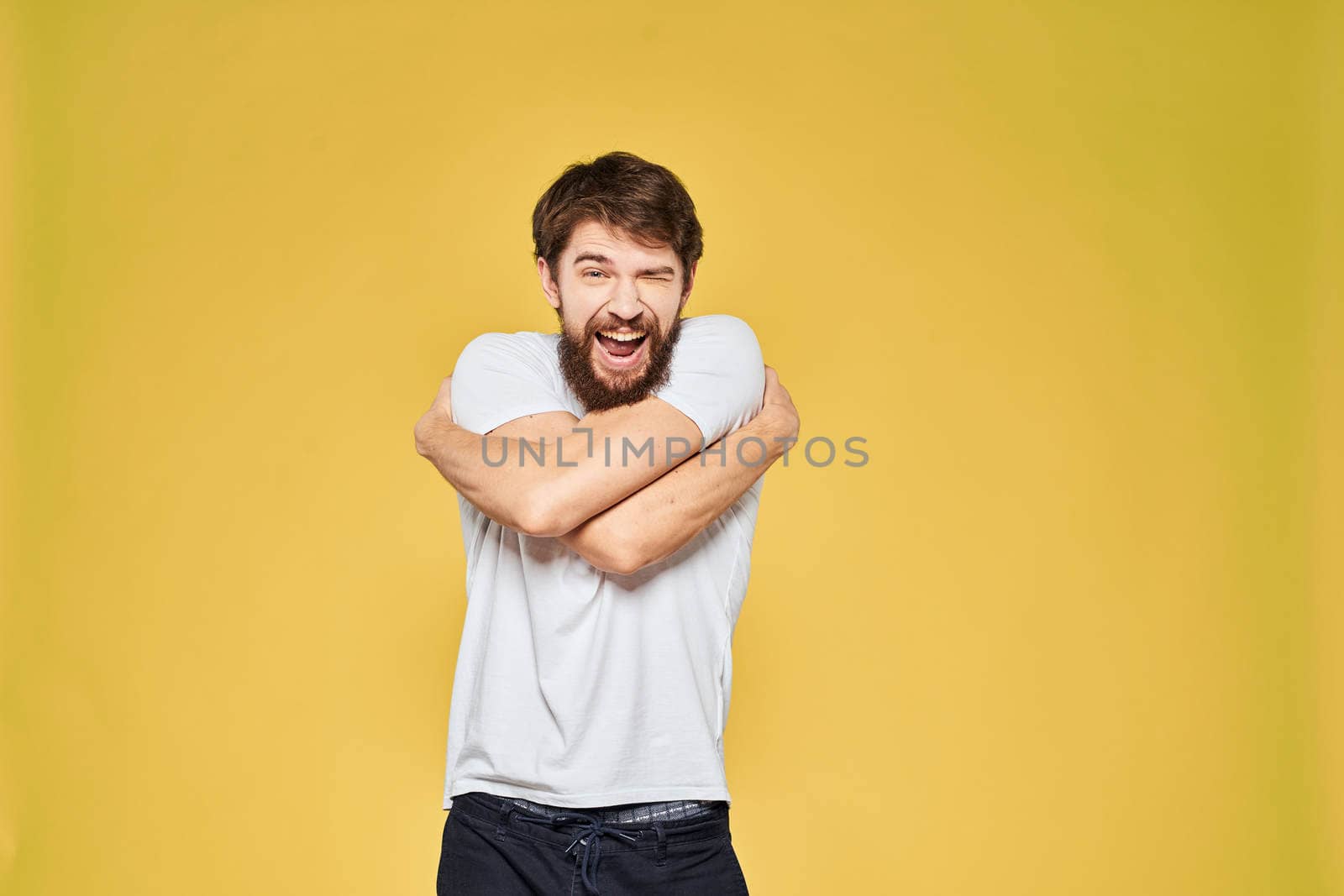 Man gesturing with hands emotions lifestyle white t-shirt yellow isolated background. High quality photo