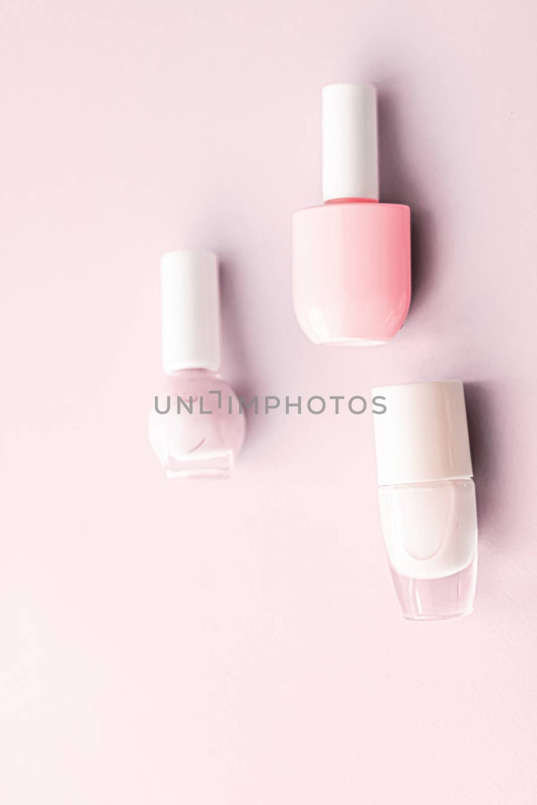 Nail polish bottles on blush pink background, beauty branding