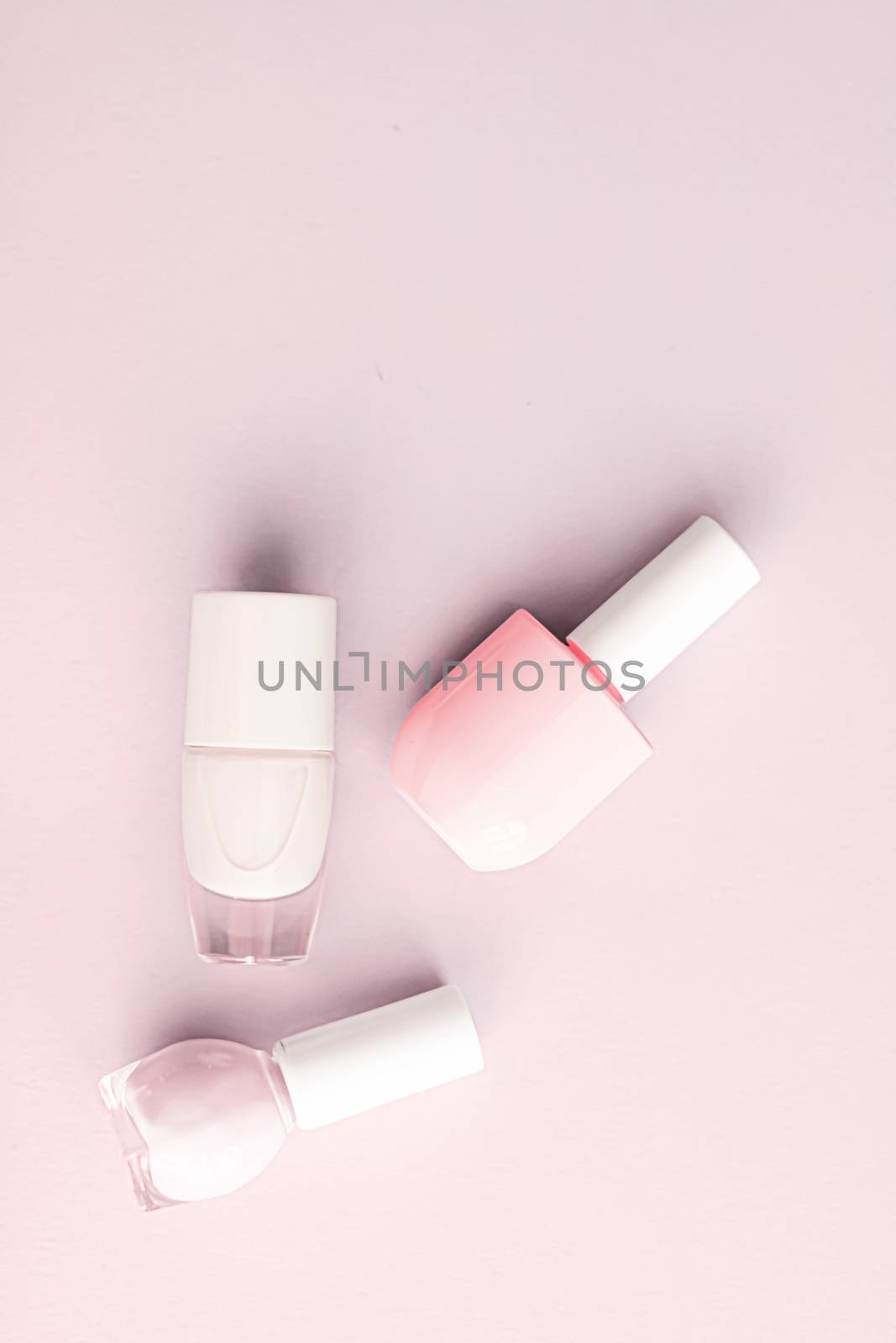 Nail polish bottles on blush pink background, beauty branding