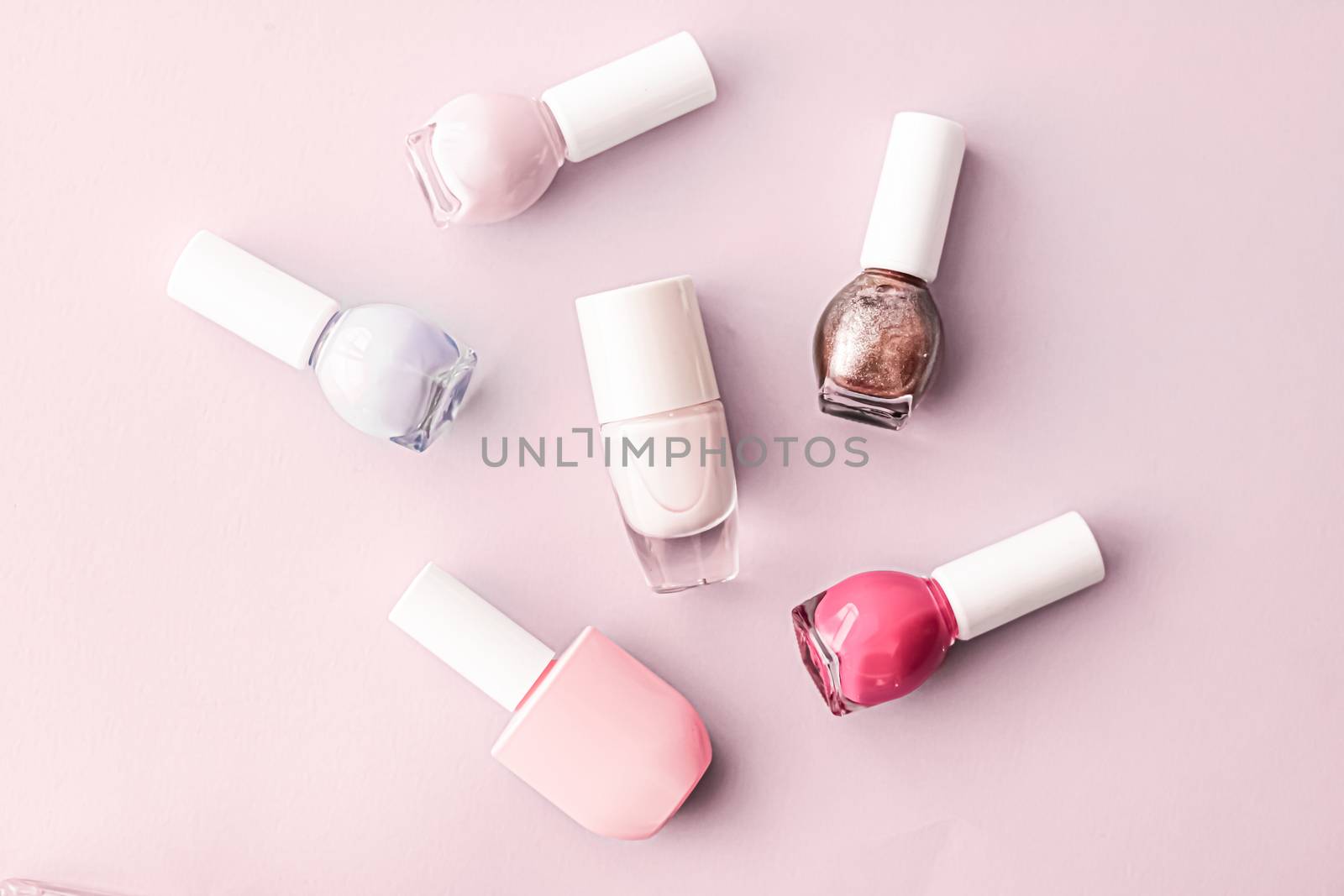 Nail polish bottles on blush pink background, beauty branding