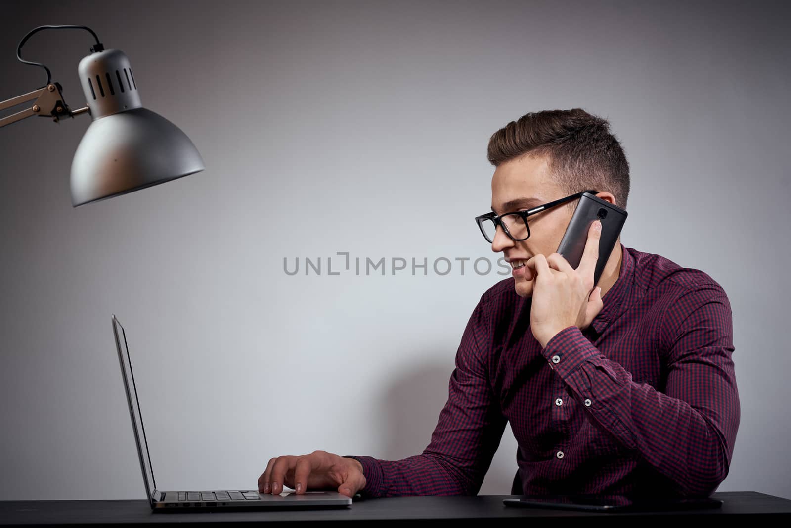 businessman in glasses and a shirt sits at a table with open laptops Coffee Space mobile phone. High quality photo