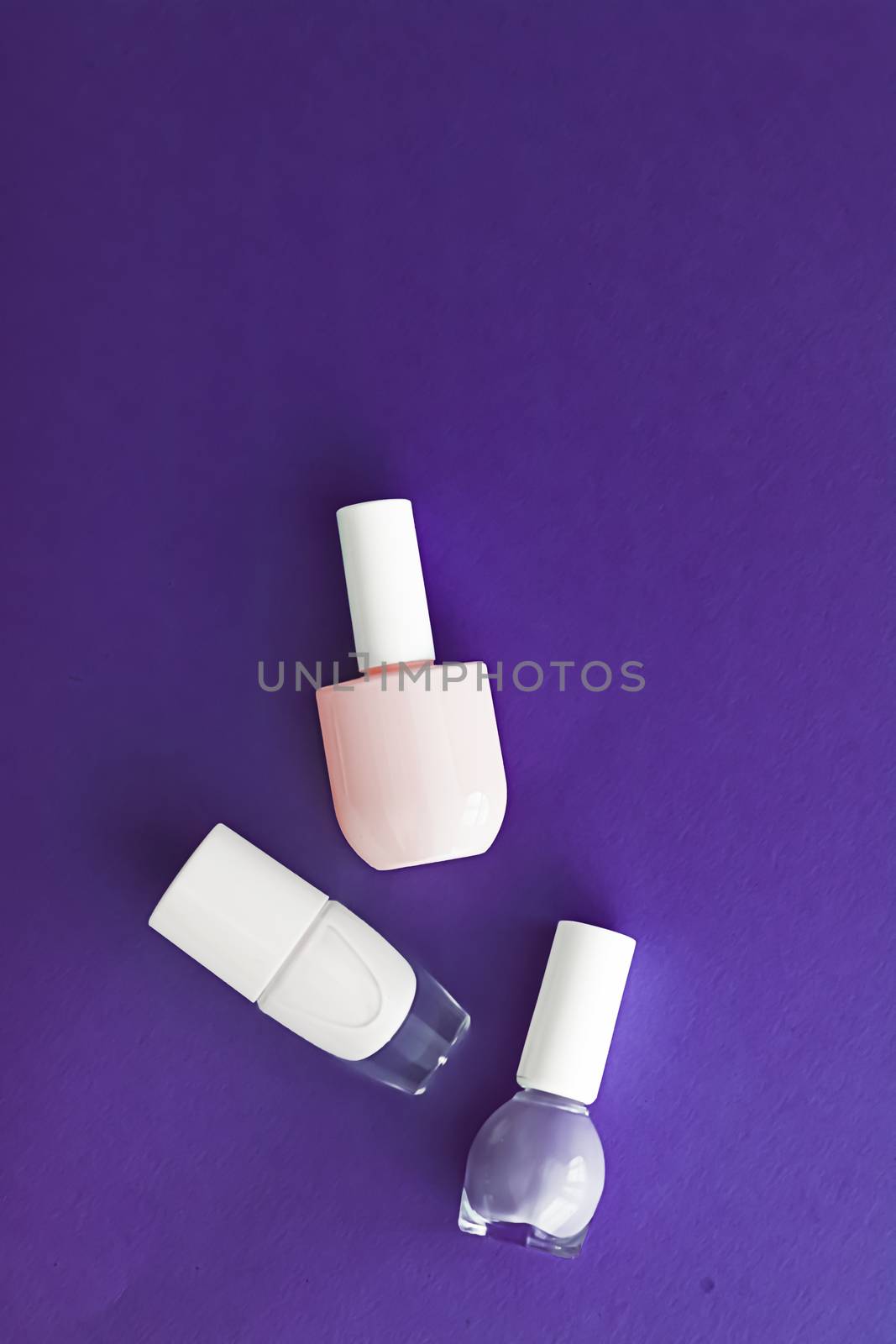 Nail polish bottles on dark purple background, beauty branding