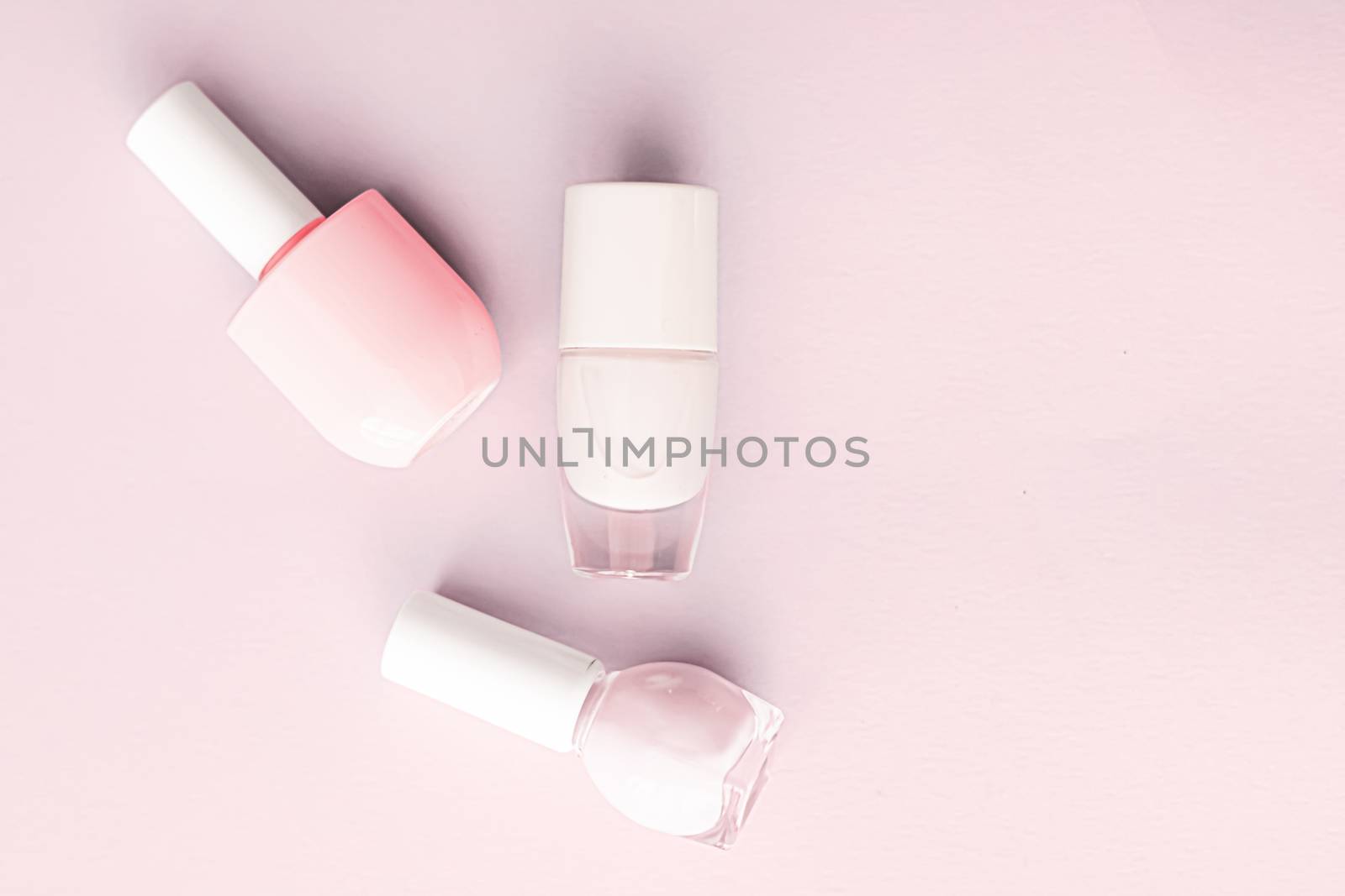 Nail polish bottles on blush pink background, beauty branding