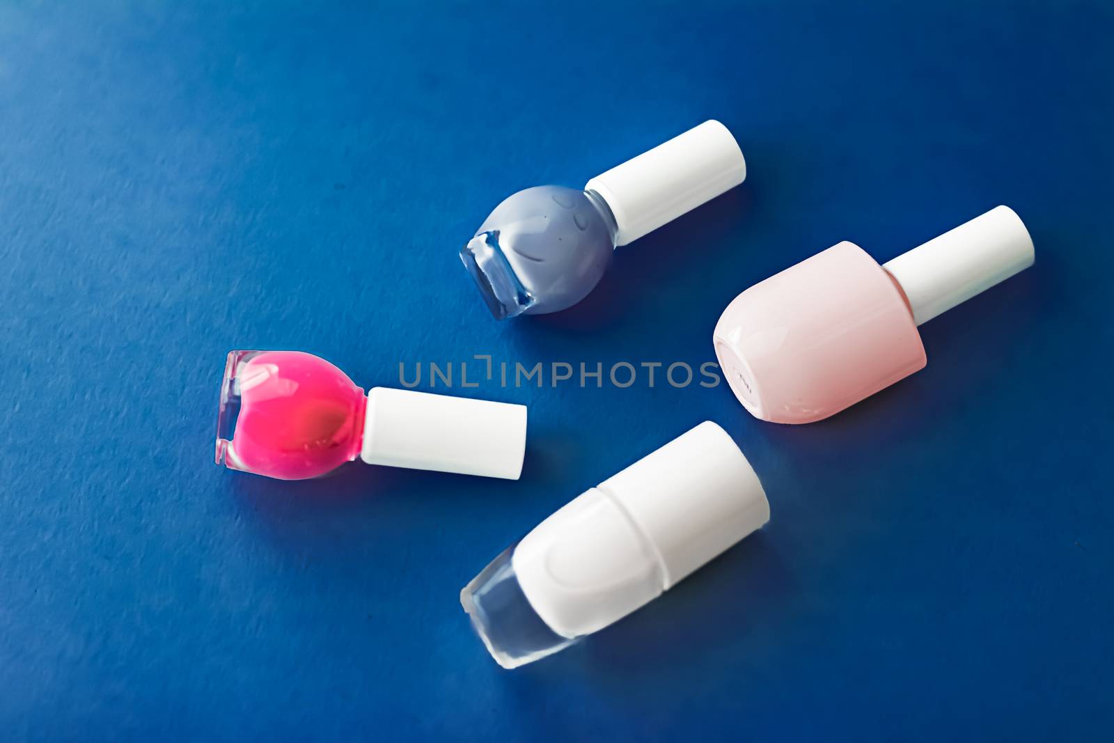 Nail polish bottles on dark blue background, beauty branding