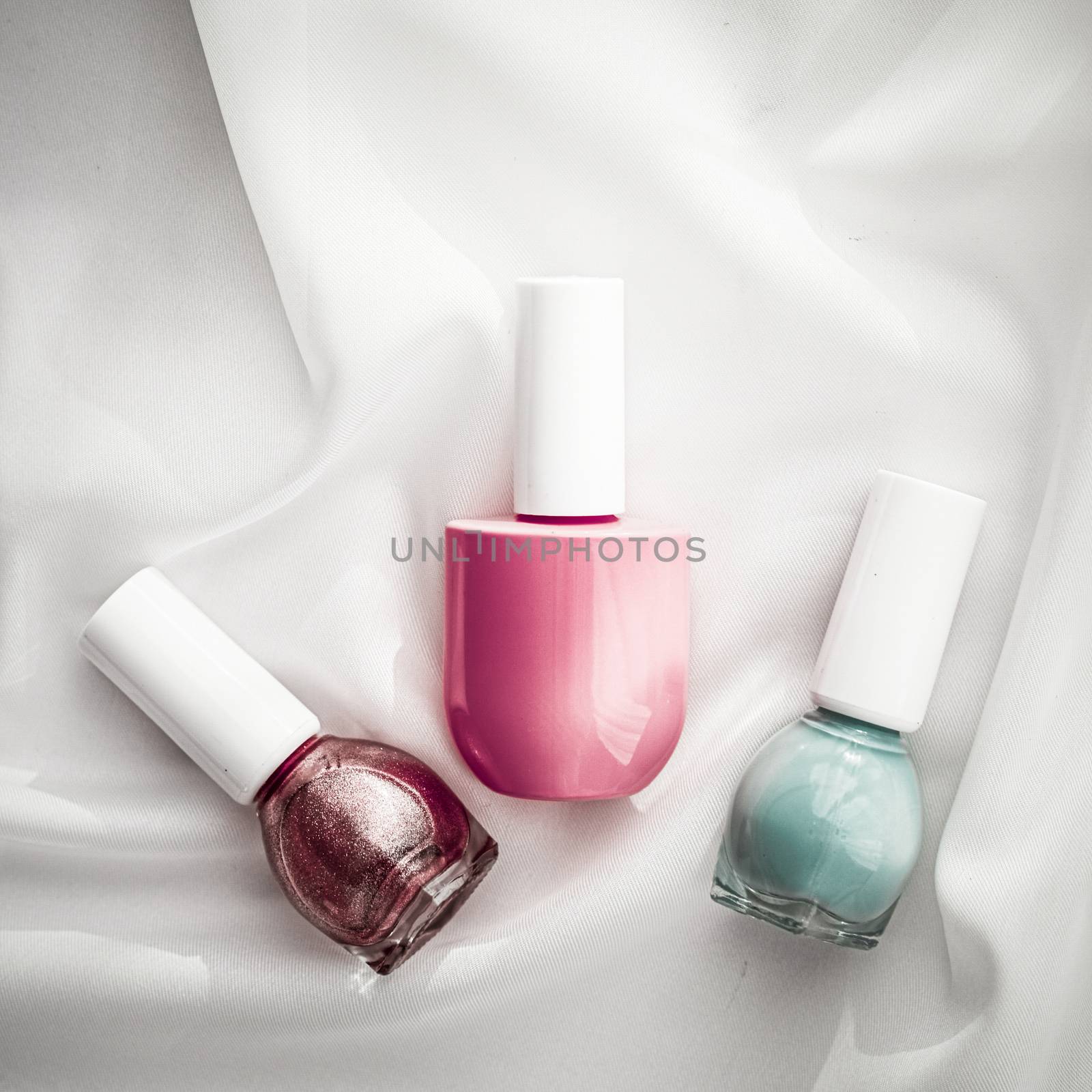 Nail polish bottles on silk background, french manicure products by Anneleven