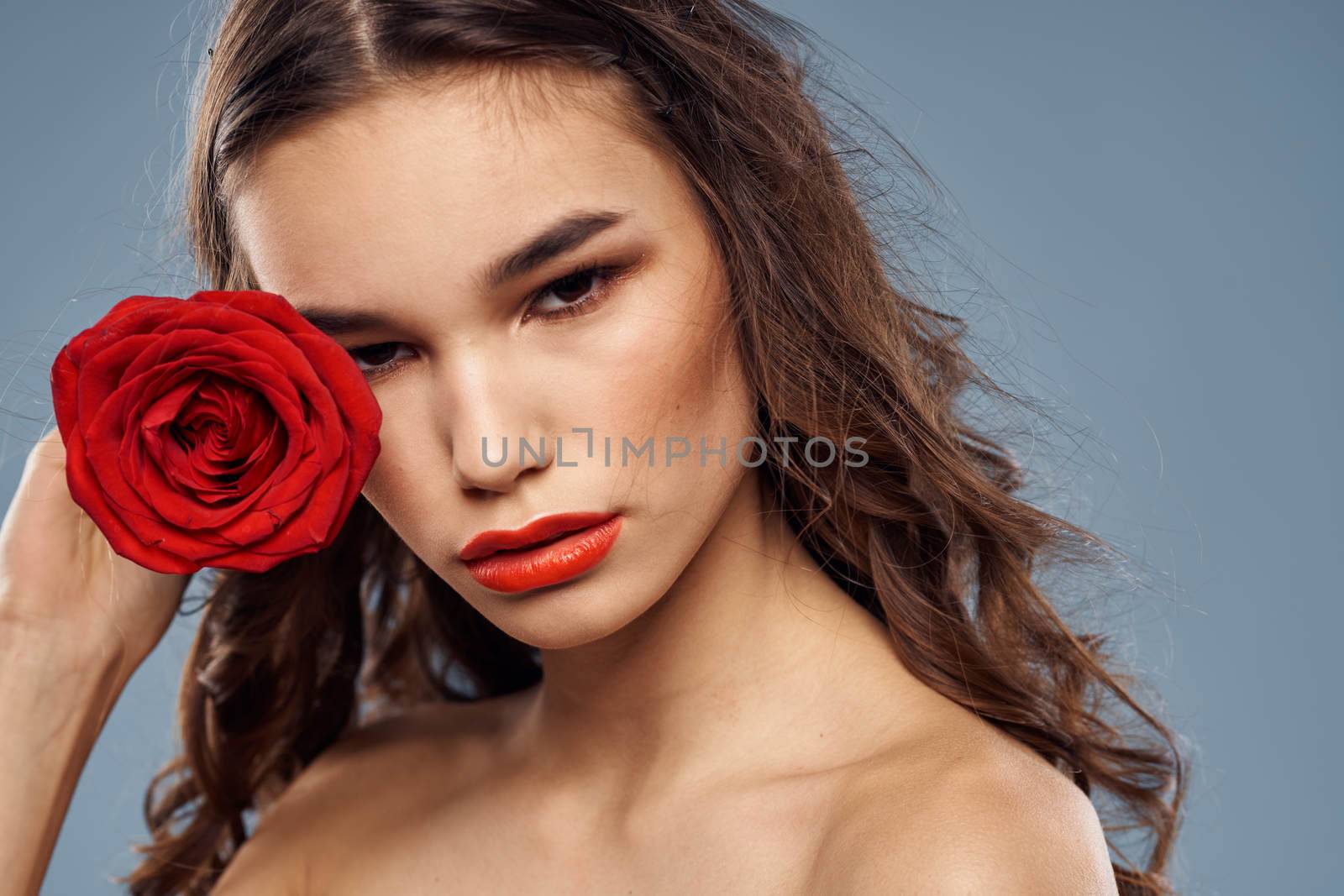 Portrait of a woman with a red rose in her hands on a gray background naked shoulders evening makeup by SHOTPRIME
