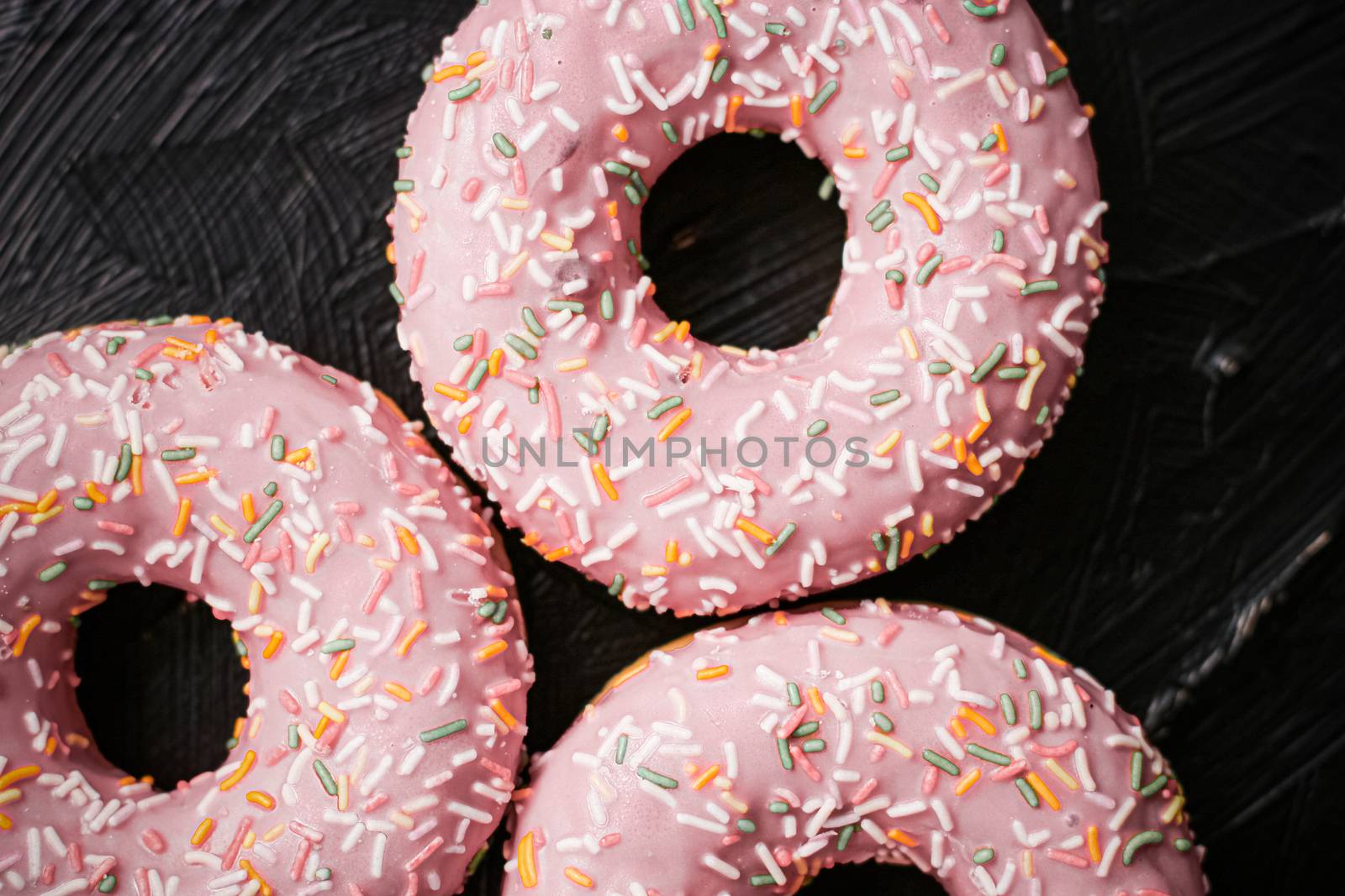 Frosted sprinkled donuts, sweet pastry dessert on rustic wooden  by Anneleven