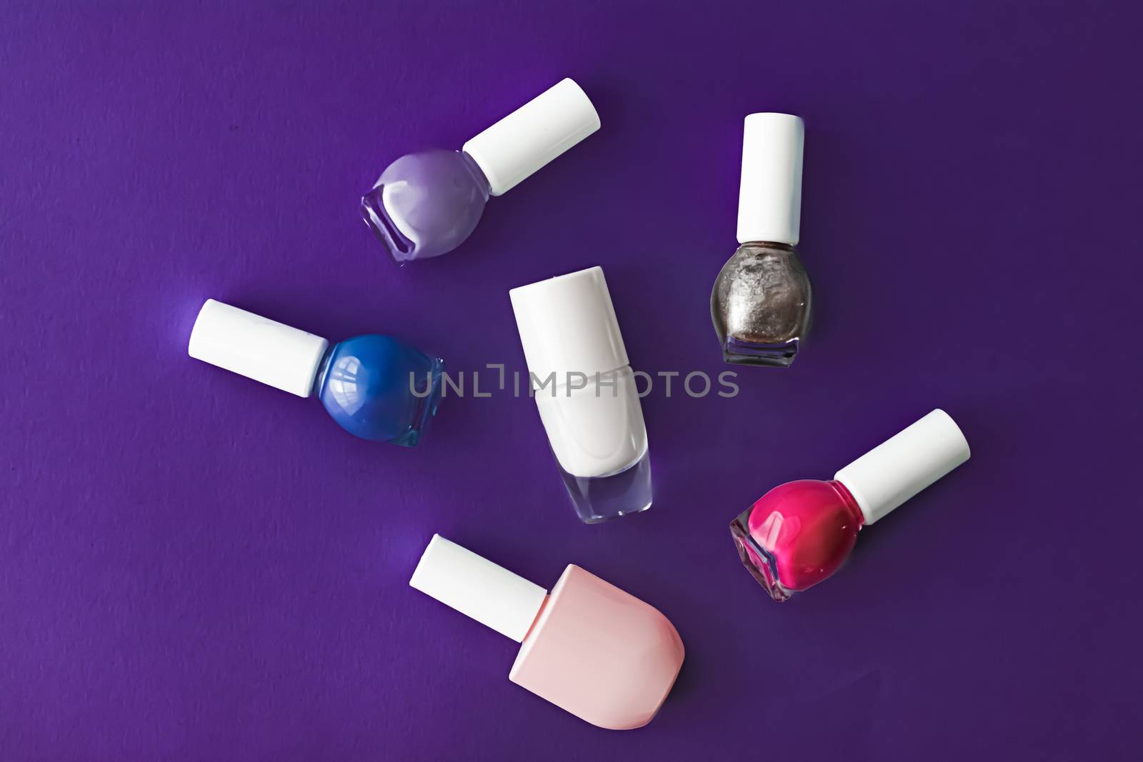 Nail polish bottles on dark purple background, beauty branding