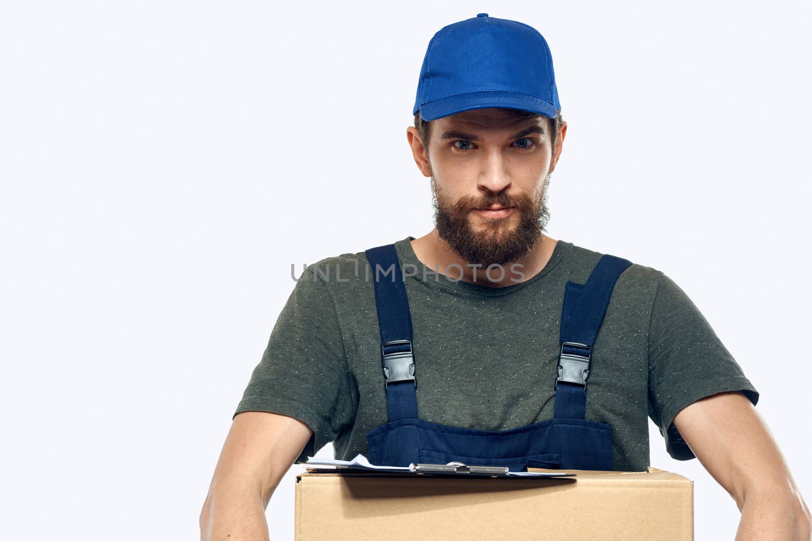 Working male courier with box in hand documents delivery service light background by SHOTPRIME