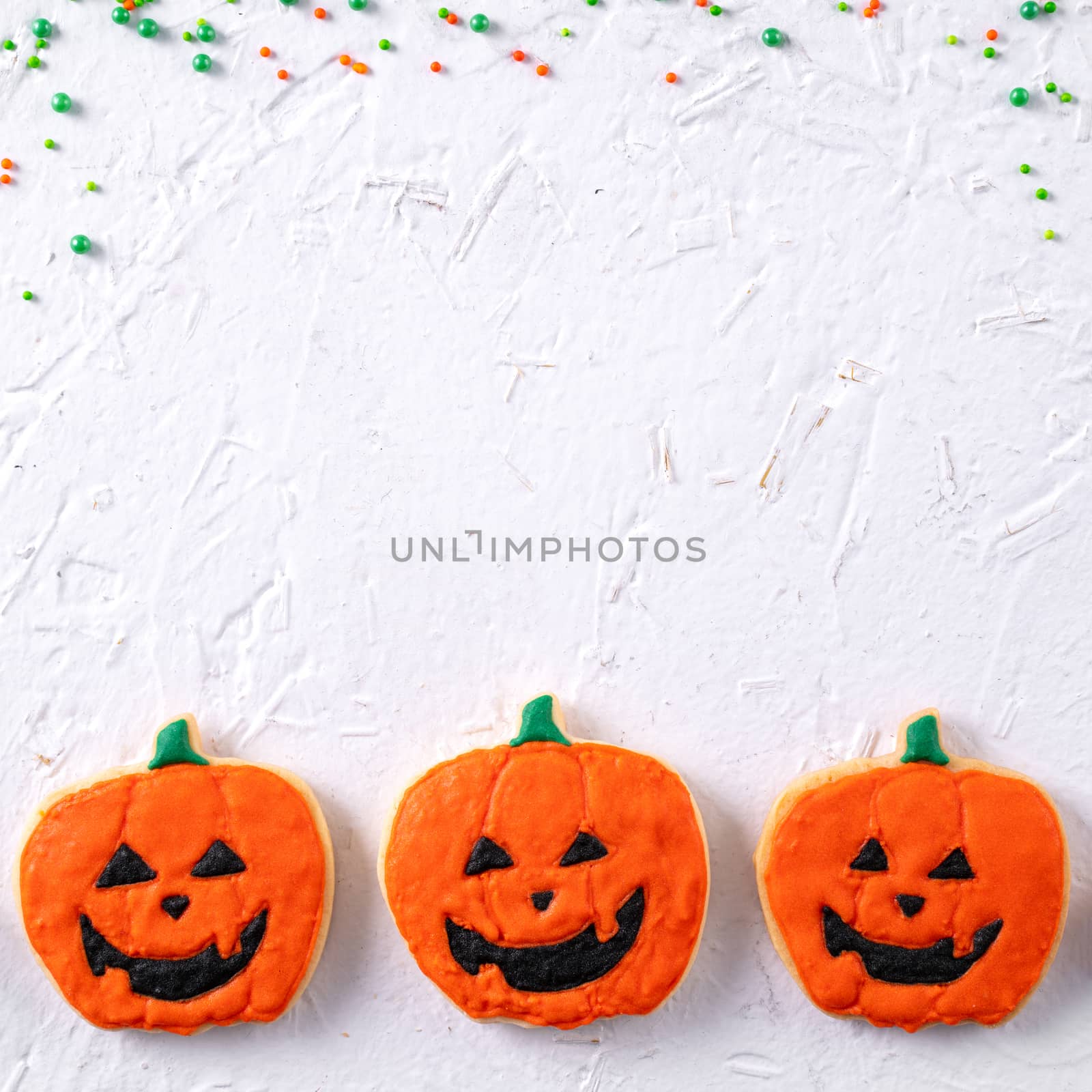 Top view of Halloween festive decorated icing gingerbread sugar cookies on white background with copy space and flat lay layout.