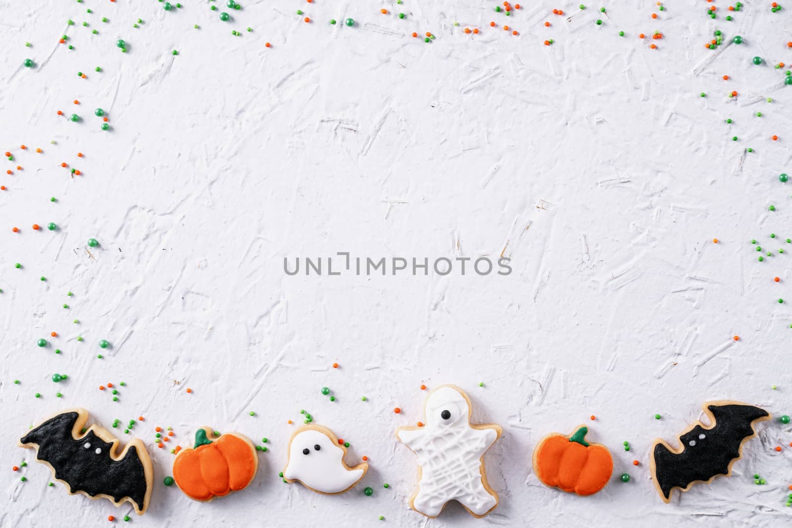 Top view of Halloween festive decorated icing gingerbread sugar cookies on white background with copy space and flat lay layout.