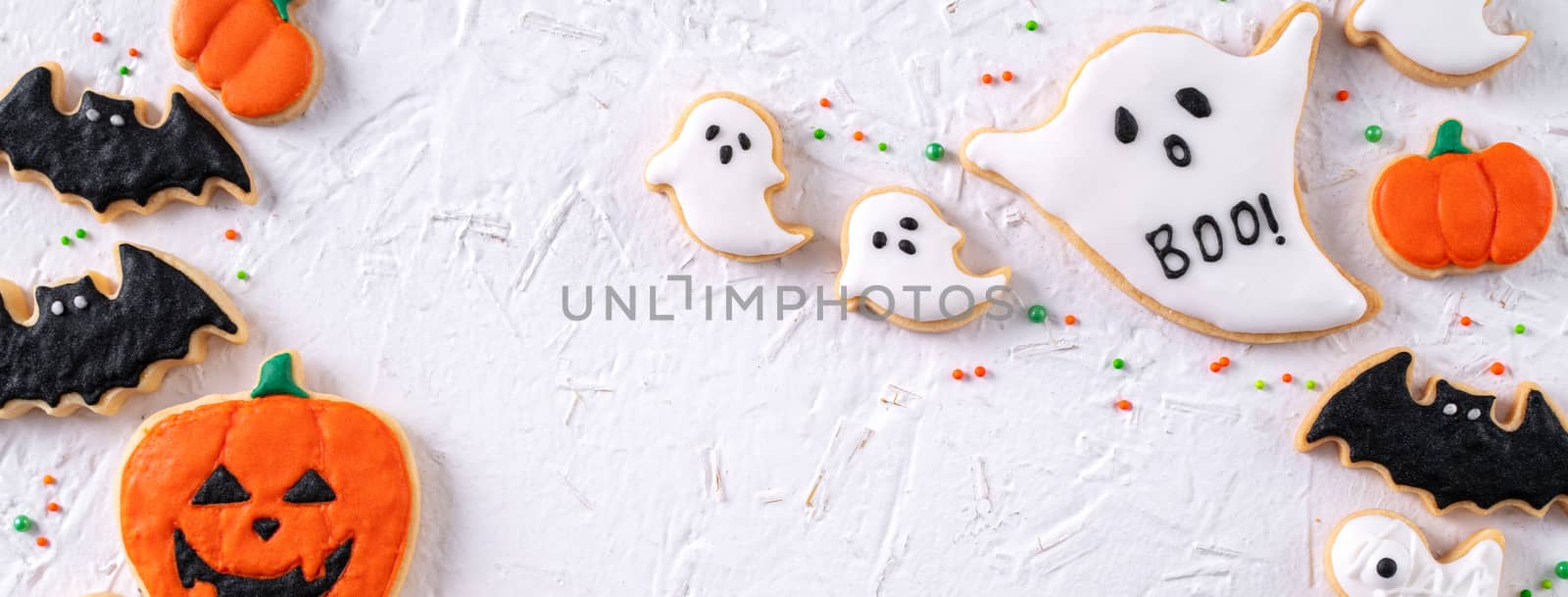 Top view of Halloween festive decorated icing gingerbread sugar cookies on white background with copy space and flat lay layout.