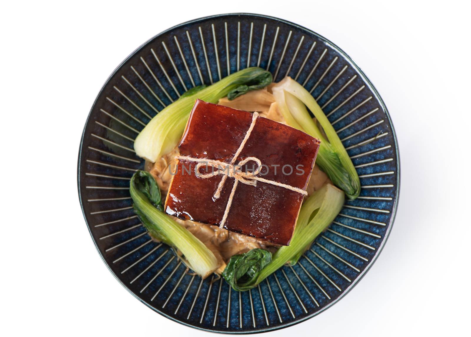 Isolated Dong Po Rou (Dongpo pork meat) in a beautiful plate with green vegetable, traditional festive food for Chinese new year cuisine meal, close up.