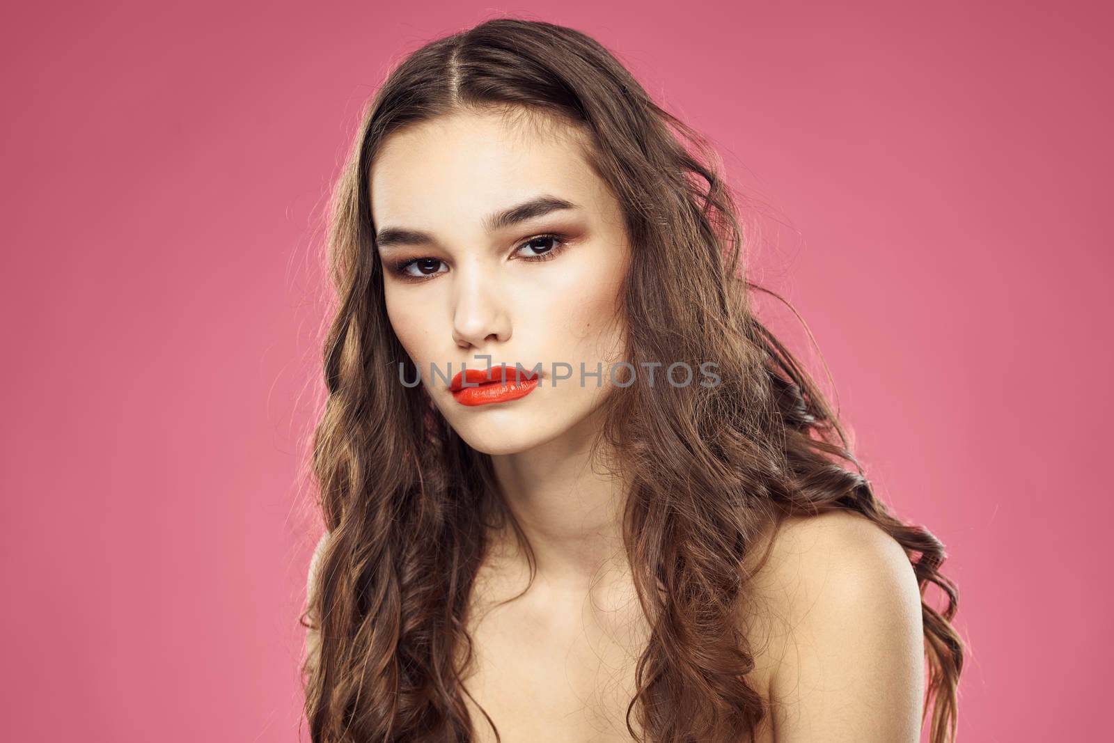 Attractive woman fashionable hairstyle bared shoulders and red lips pink background. High quality photo