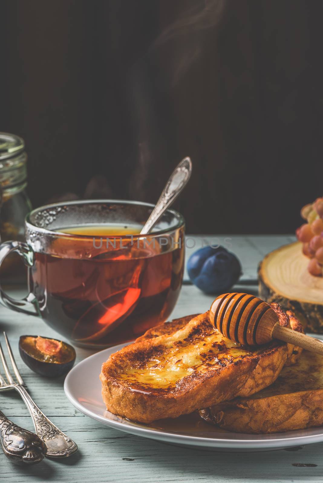 Healthy breakfast concept. French toasts with honey, fruits and tea over white wooden background