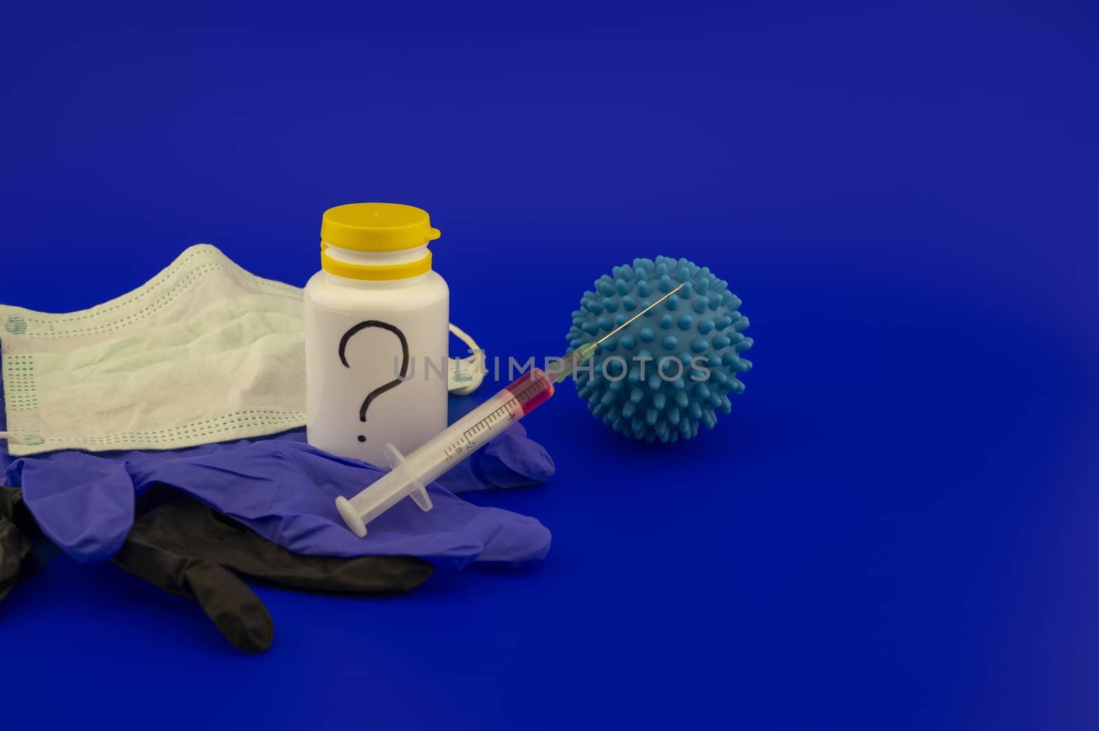 Concept of research for a Covid-19 vaccine with a conical lab flasks with yellow and red solutions alongside a hypodermic syringe and blue virus molecules over a blue background with copy space