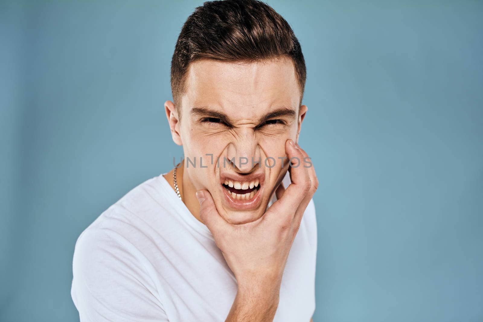 emotional displeased man cropped view white t-shirt blue background. High quality photo