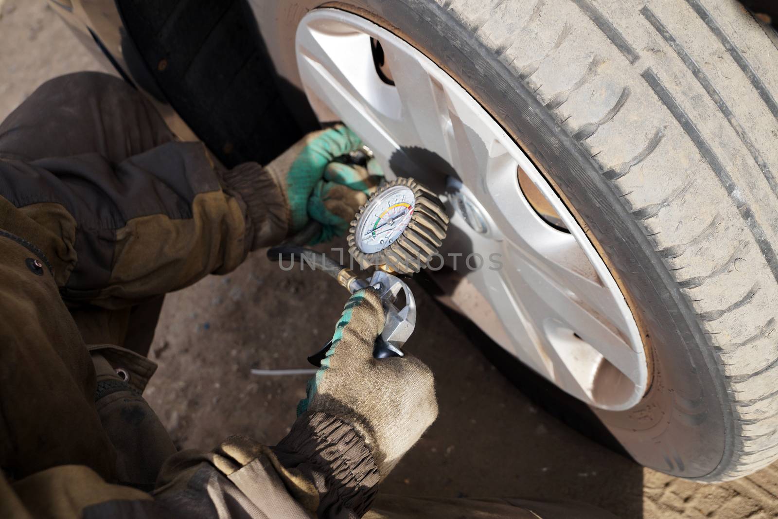 car mechanic checks the pressure in the car wheel, close up