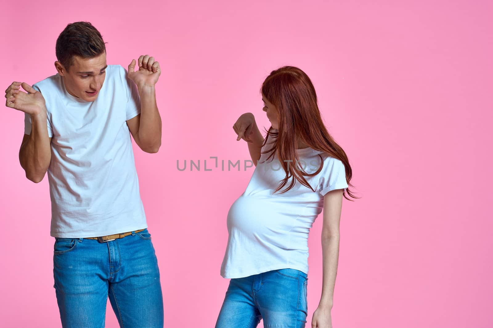 pregnant mom and happy father on pink background Young family waiting for baby by SHOTPRIME